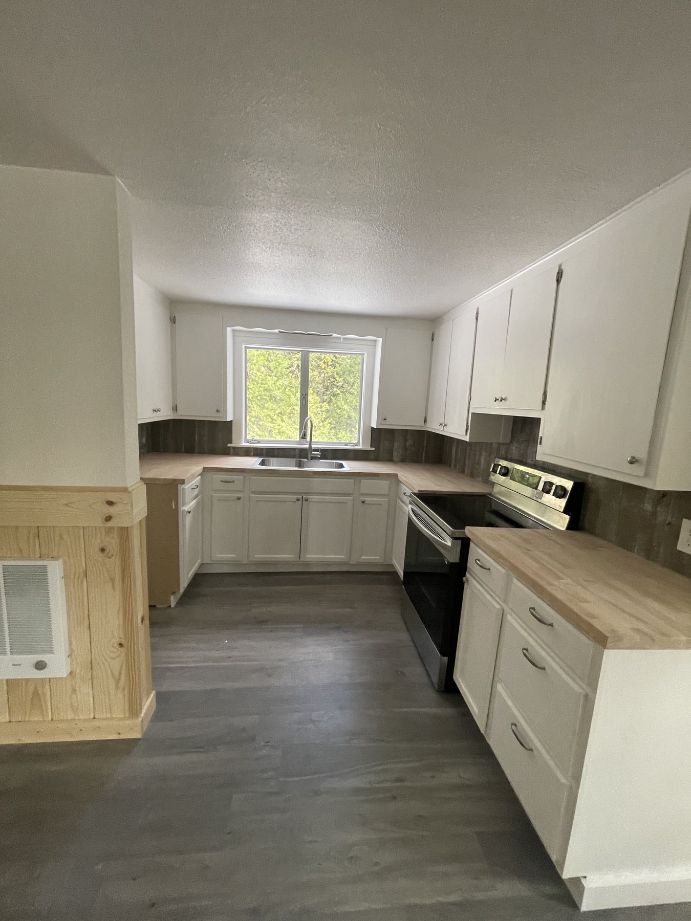 The kitchen before, with gray floors and white cabinets